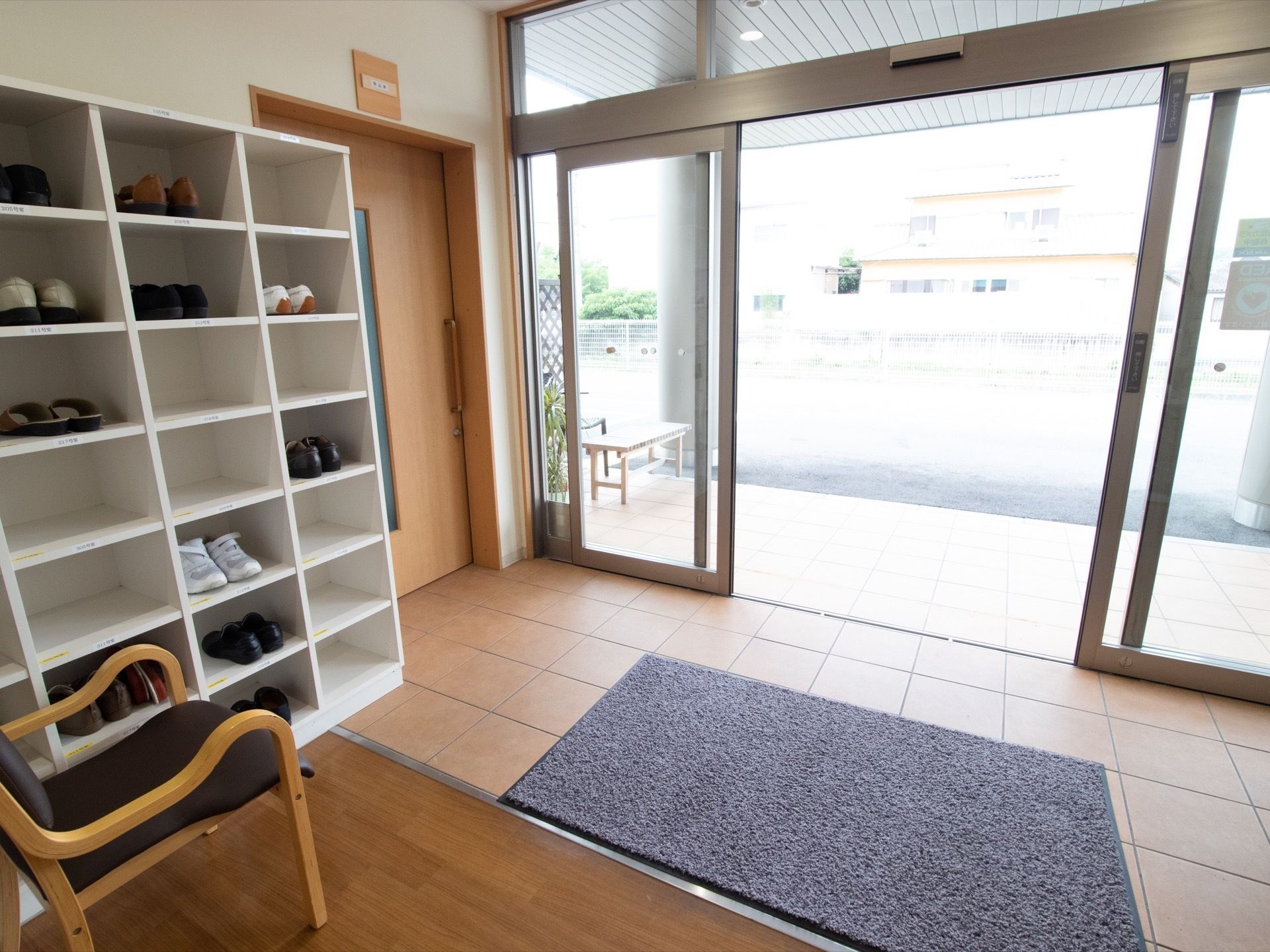 両開きのガラス扉から光が差し込む玄関である。バリアフリー設計で段差がなく、足元が不安な方も通行しやすい。