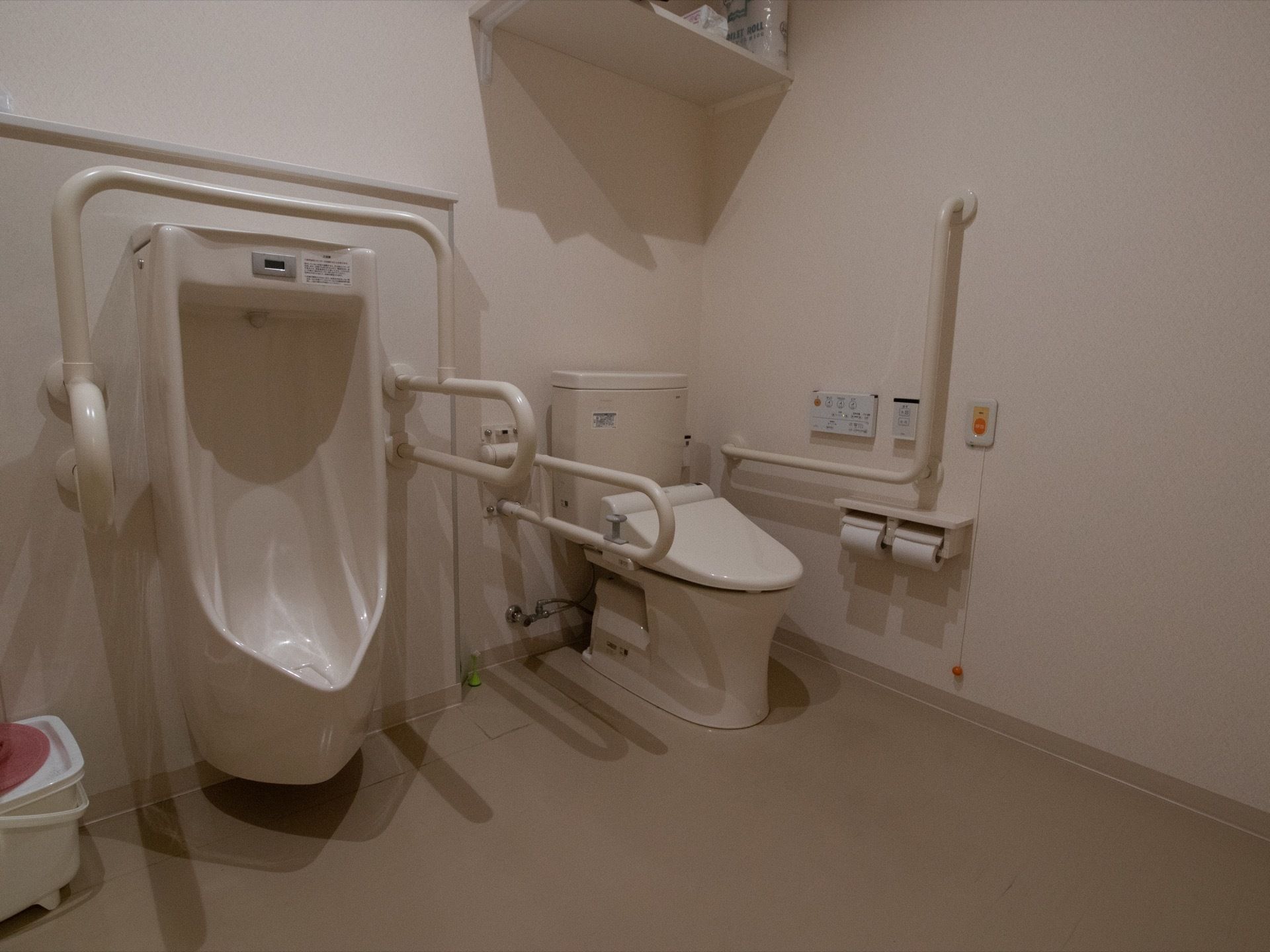 男性用小便器が設置されているトイレである。小便器の両側や洋式便座の両側に手すりがしっかりと備わっている。