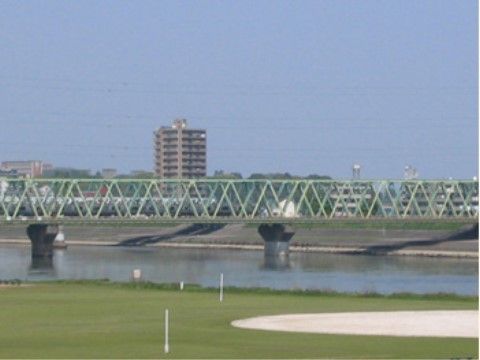 施設の近くを流れる大きな川にかかる橋と、河川敷の風景である。春には桜並木を楽しみながら散歩をすることができる。