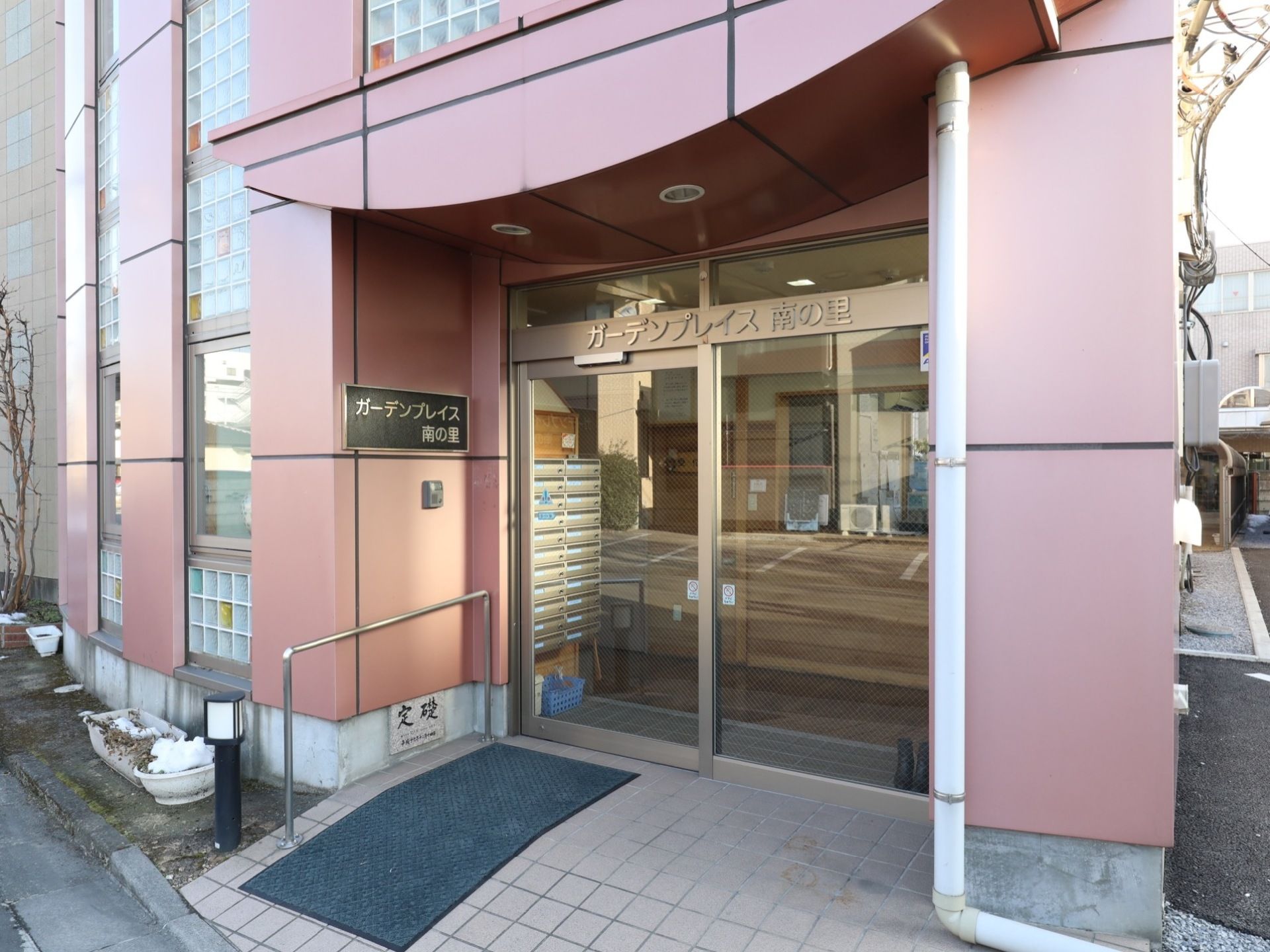 玄関入口は透明な自動ドア仕様で段差がなく、手すりが付けられ滑り止めマットが敷かれている。壁は薄ピンク色である。