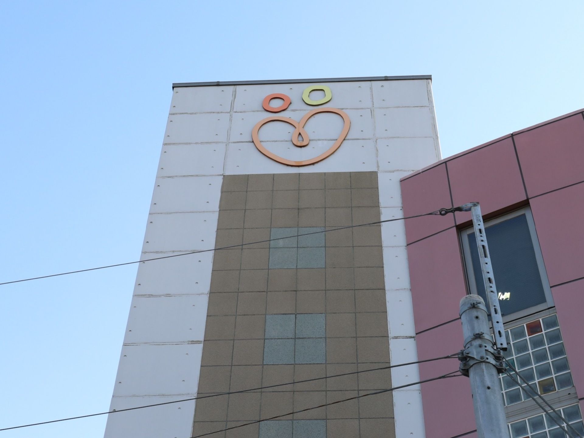 施設建物の上部にはシンボルマークがあり、人が2人寄り添っている感じとハートを表しているように見える。