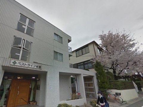 施設は白い外観で3階建てになっている。茶色い玄関扉の両側はガラス張りになっており、結ばれたカーテンがかけられている。