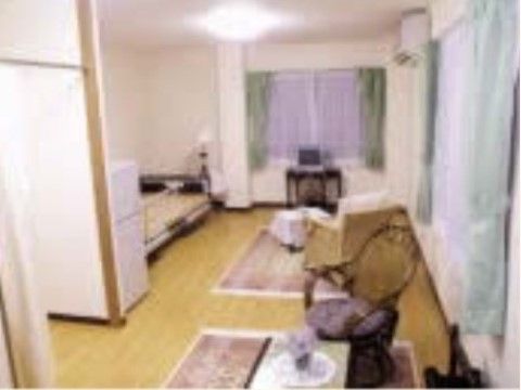 居室には窓が2か所にあり、それぞれカーテンがかけられている。ベッドの横側には小さめのテーブル、椅子、テレビが用意されている。