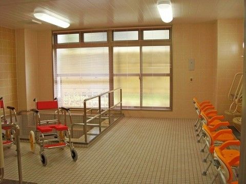 タイル張りの開放的な大浴場である。広い洗い場には、浴室用の車椅子やシャワーチェアが複数用意されている。