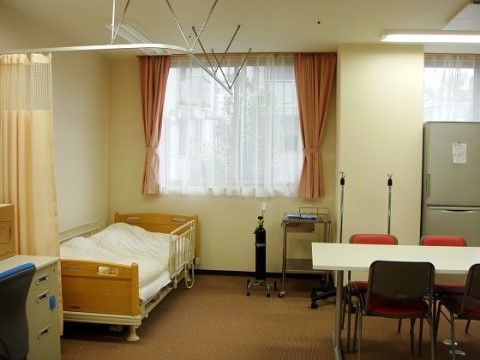 部屋の隅にベッドが設置されており、カーテンで仕切れるようになっている。手前のスペースには、冷蔵庫やデスクなどが置かれている。
