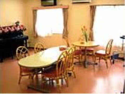窓が２枚ある部屋は壁際にピアノがある。部屋の中心には、藤製の椅子が並んだダイニングセットが２つ並んでいる。