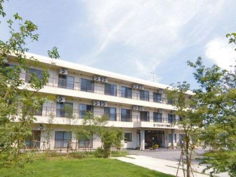 白く新しい３階建ての建物で、敷地内の芝生と植栽の緑が美しい。正面は舗装されており、玄関前には鉢植えが置いてある。