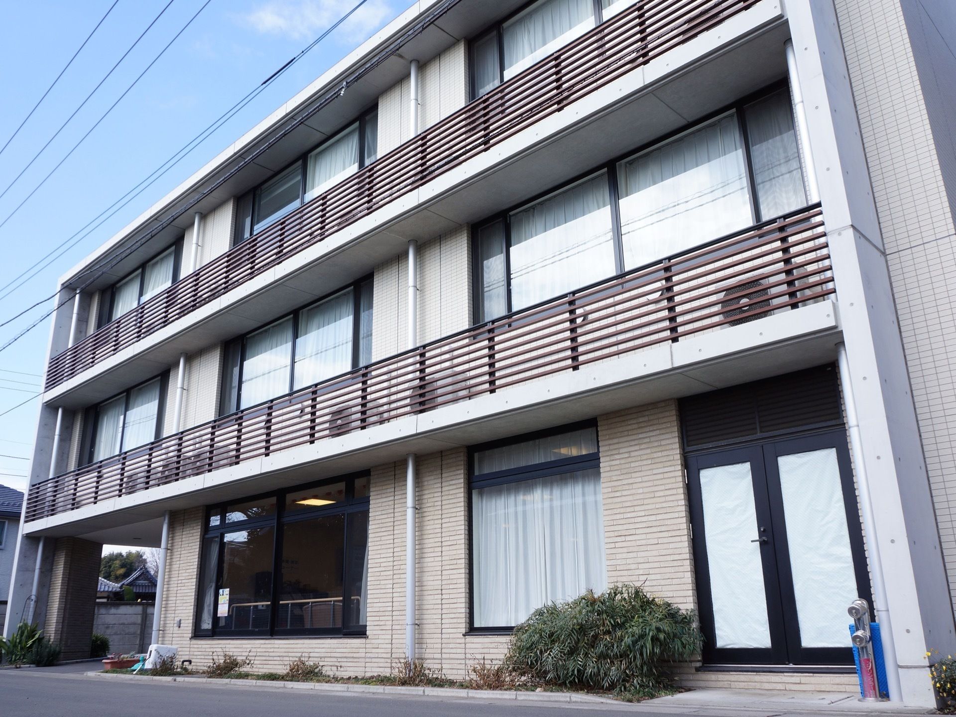 ３階建てのスタイリッシュな外観の施設。それぞれの部屋に窓が取り付けられていて、光が差し込む明るい室内になっている。
