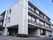 施設の建物は白い外壁の３階建てである。１階部分には車の入り込めるようになっている出入口がある。どの居室もバルコニーの窓が大きい。