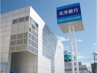 建物の前に建っている、白い柱で支えられた銀行の青い看板