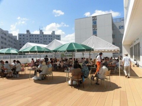 緑のパラソルが立てられたテーブルや白いテントが置かれたテラス