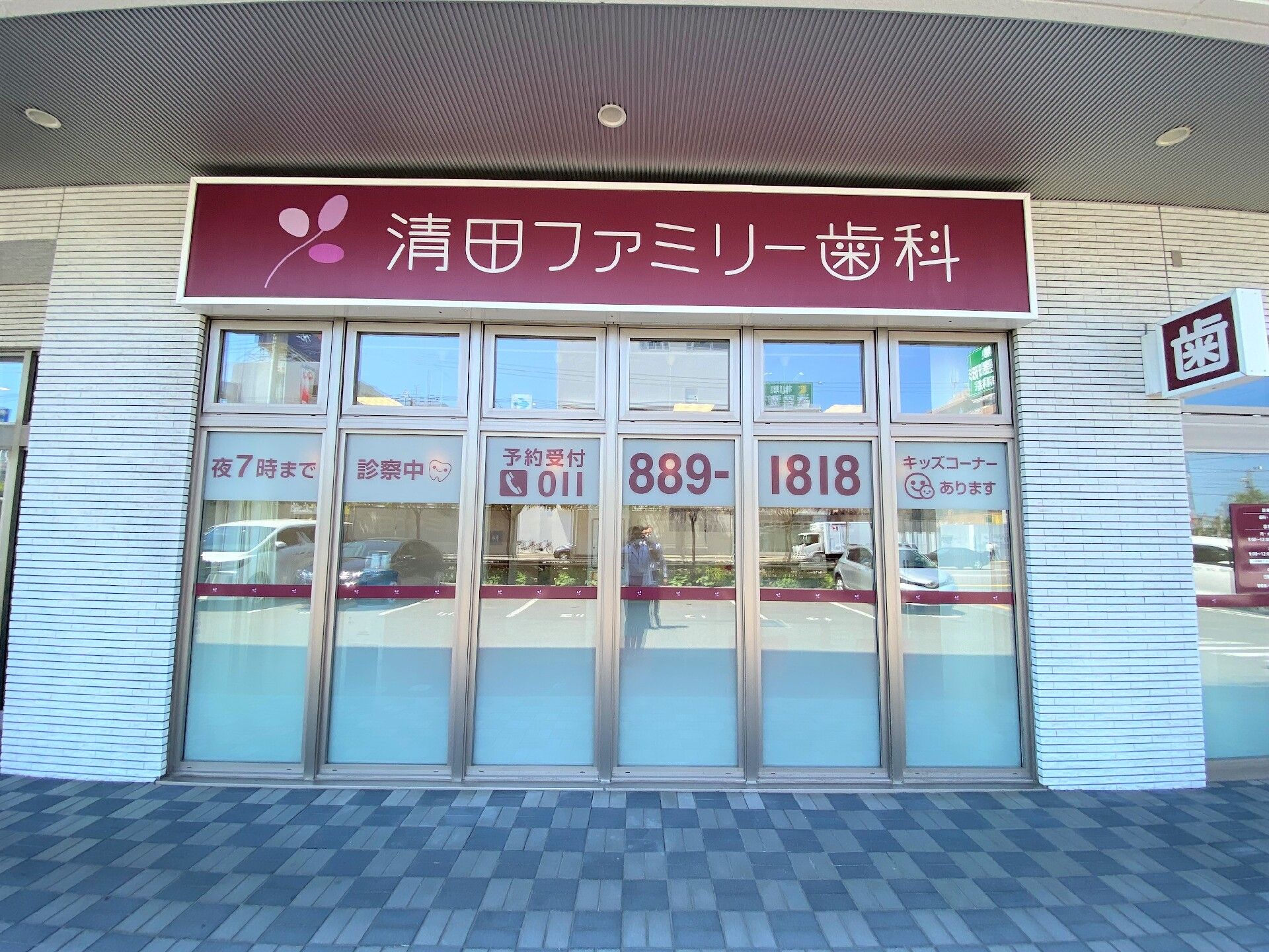 ガラス窓に営業時間や受付番号が貼られた歯科の外観