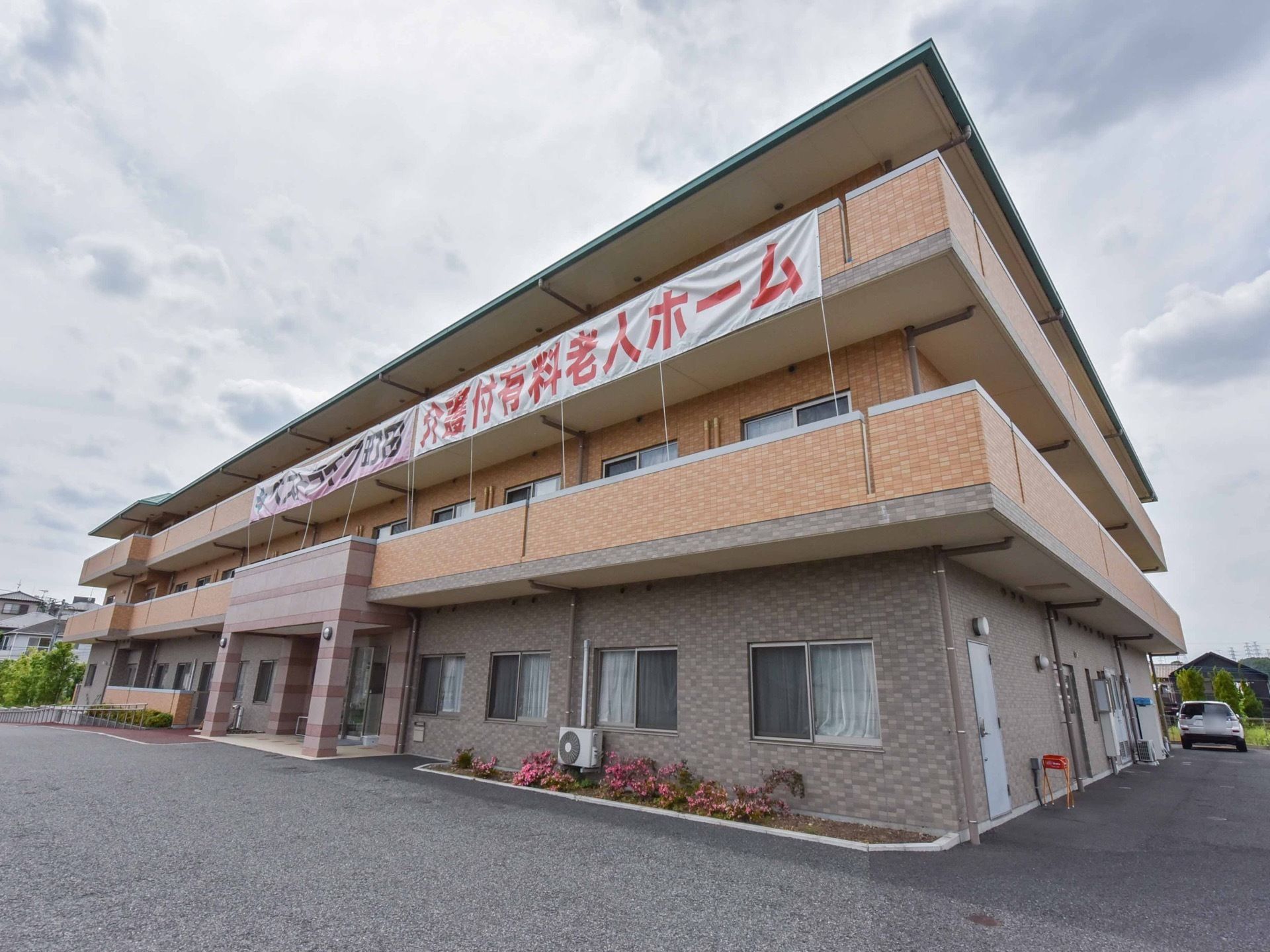 ブラウンの外壁の３階建ての建物である。玄関前のスペースには屋根を設置しており、雨の日も濡れることなく施設内に入ることができる。