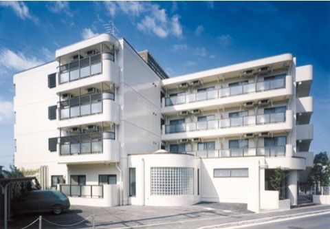 真っ白な清潔感のある４階建ての建物。ベランダ側には、すりガラスがあり開放感がある。駐車場も完備している。