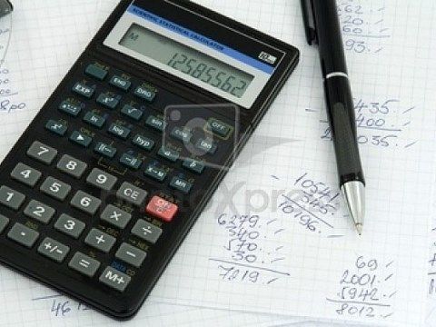 筆算が記載されている紙と、上に置かれた黒い筆記用具と電卓