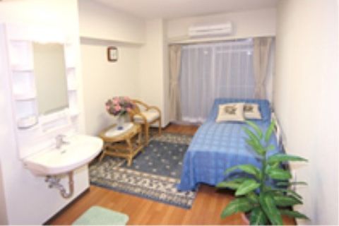 大きな観葉植物が飾られた居室内には、白く清潔感のある洗面台が設置されていて、洗面台前の鏡の横には小物を置く棚がついている。