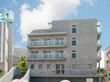 明るめのグレーの外壁が爽やかな印象の4階建ての建物。２階から４階の居室部分にはベランダも設置されている。