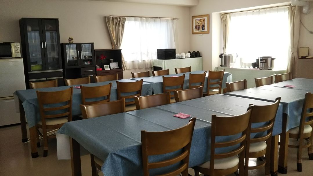 明るい光が差し込む窓際に設置された食堂のテーブル。6人が座れるイスが置いてあり、おしゃべりをしながら食事を楽しむことができる。