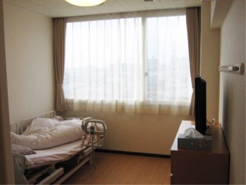 壁の幅いっぱいに開いた、カーテンが掛けられている窓が正面にある居室