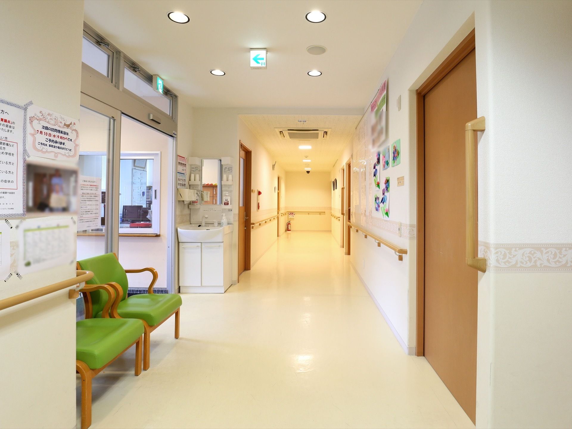 横幅の広い廊下である。壁に沿って、手すりが付いている。壁にはお知らせなどが貼られている。途中に洗面台が設置されている。