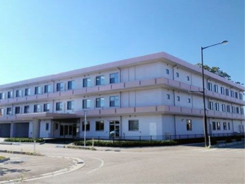 丁字路の角地に建っている、白とピンクの３階建ての建物