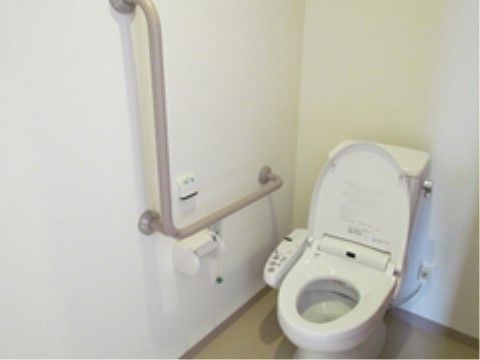 掃除が行き届いたトイレスペースは、清潔感に溢れている。立ち座りの動作が楽に行えるようにエル型の手すりを採用している。