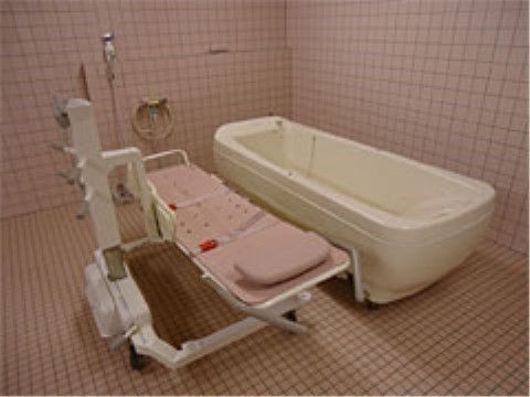 ピンクのタイル調の浴室である。寝たままの体勢で湯船に浸かれる機械浴を設置している。介護度の高い方も、介助を受けながら快適に入浴が行える。