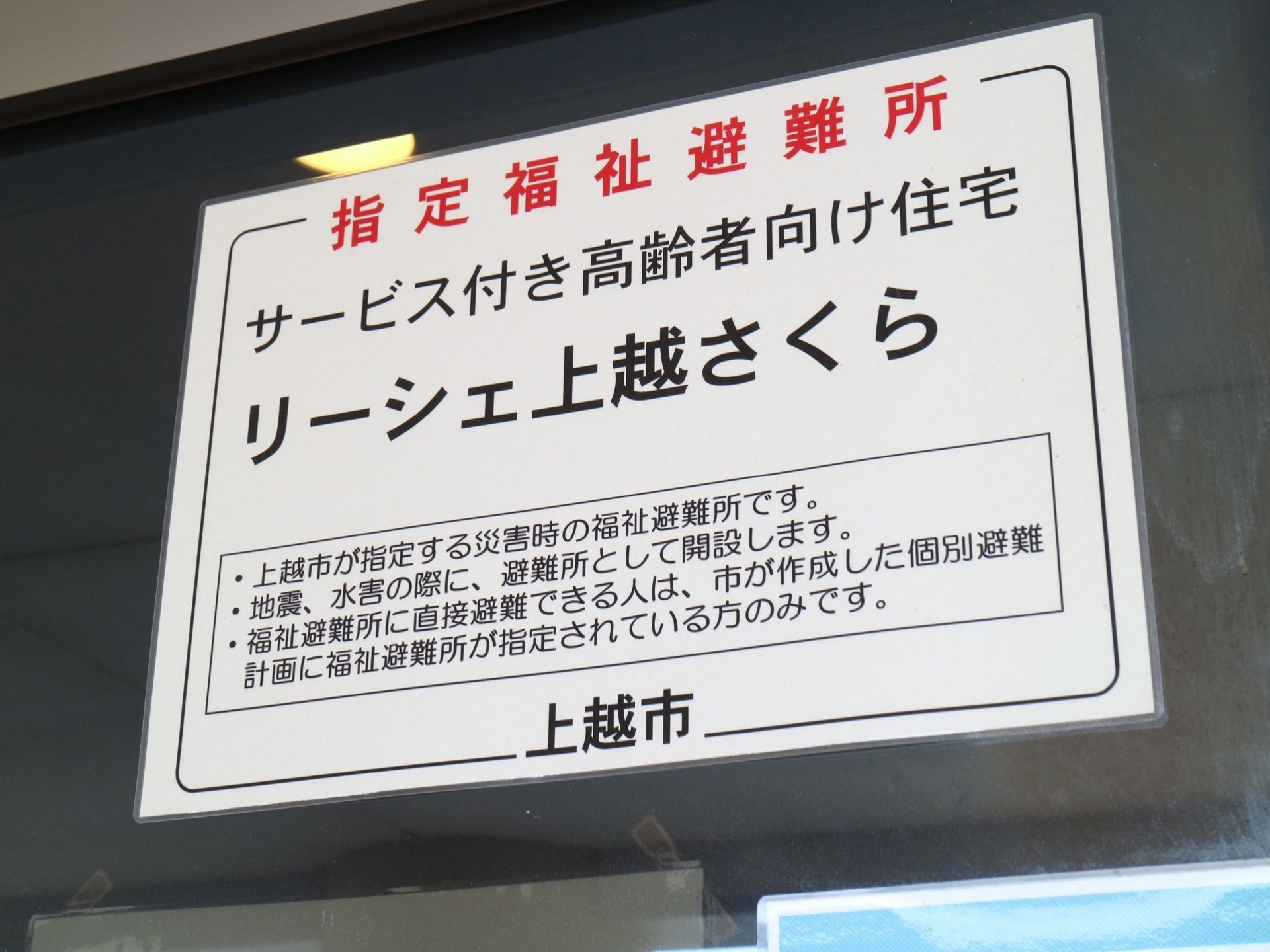 白い掲示物が貼られている。この施設は高齢者向けの住宅としてだけではなく、市の指定する避難所としての役割も果たしている。
