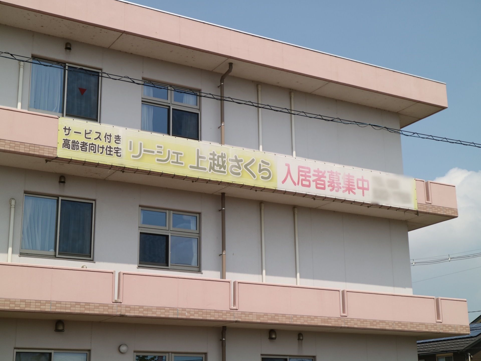 建物の側面に入居者様募集の看板が掲げられている。施設は複数階あり、多くの入居者様を受け入れることが可能である。