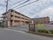 施設入口の門は大きく開いている。施設はフェンスで囲まれており、門に施設名の掛かれた看板が設置されている。