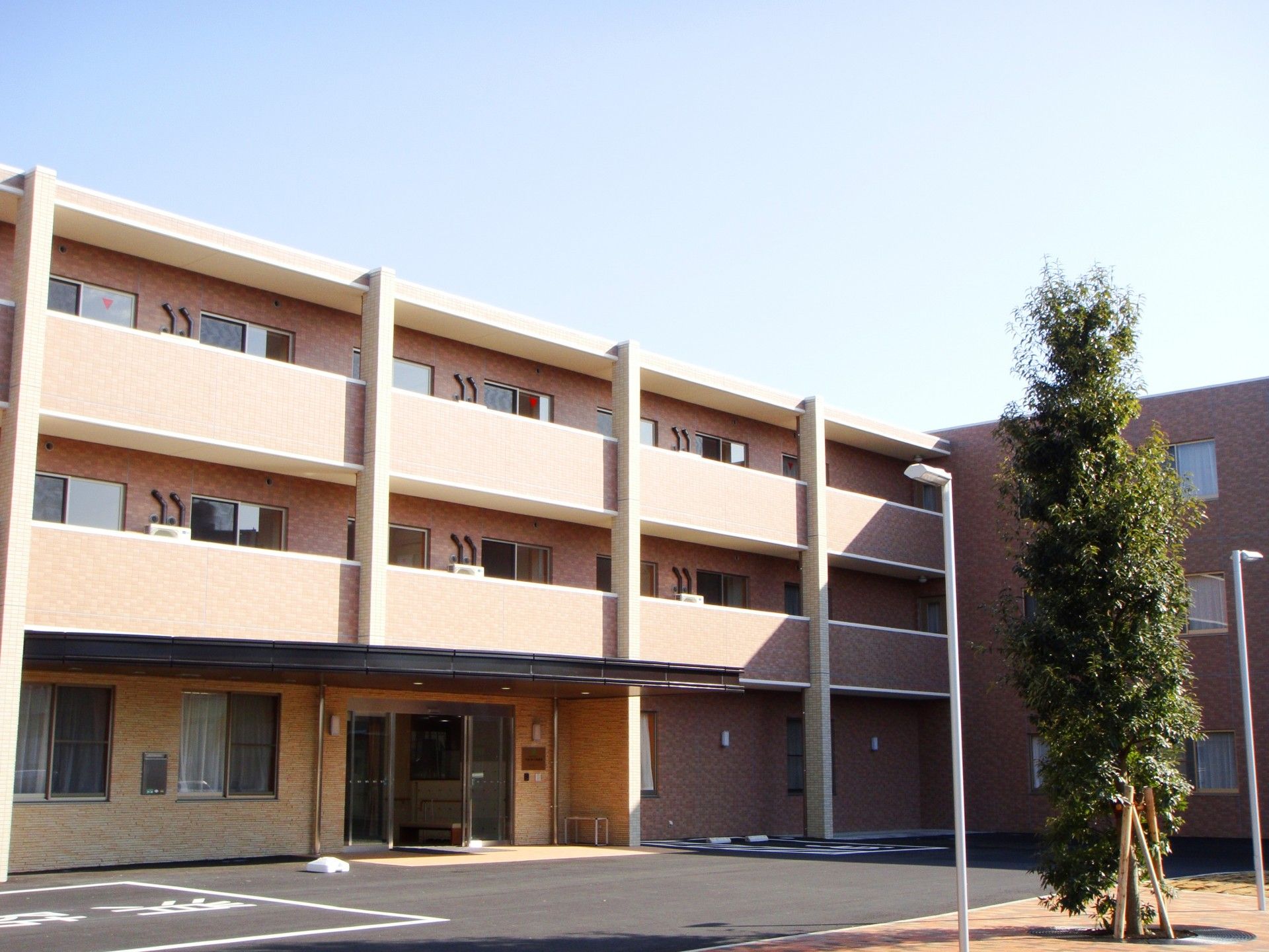 「ベストライフ相模原」の外観。広々とした大きい３階建ての老人ホームで、多くの駐車場も用意している。