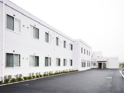 右奥に向かって真っすぐ伸びている、２階建ての白い建物