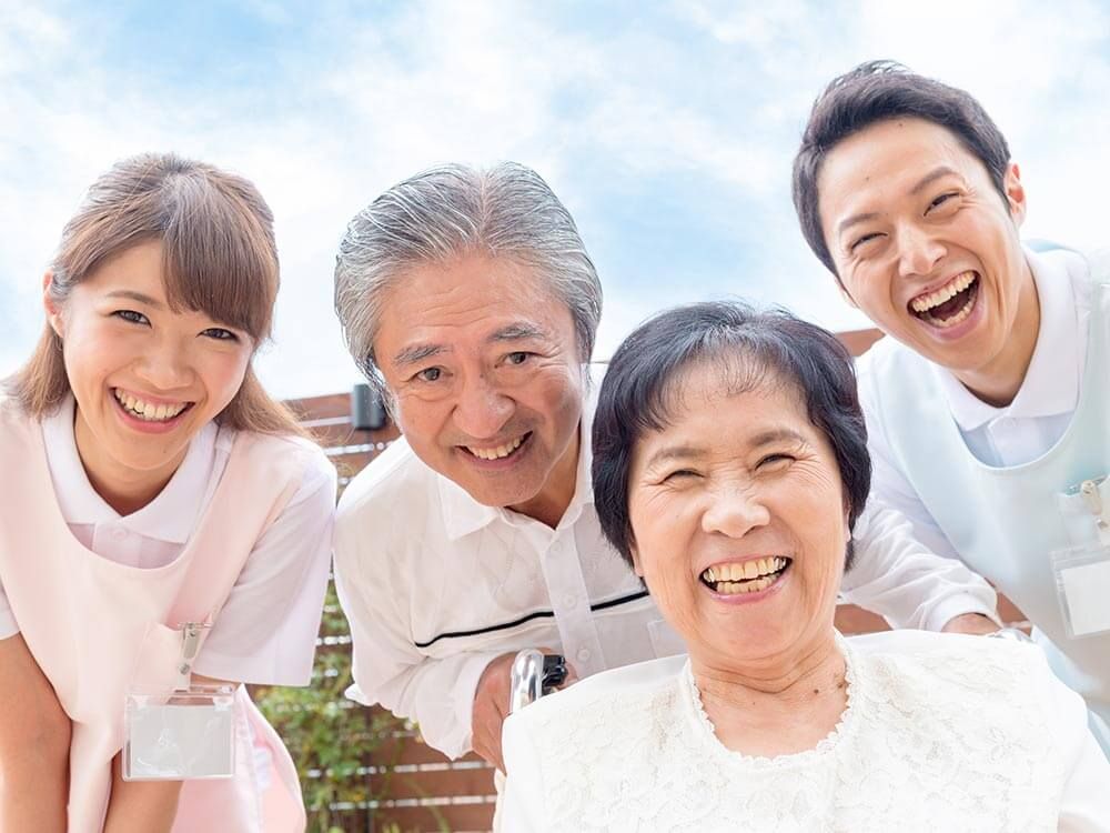 笑顔の介護士に囲まれた車椅子に乗った高齢女性
