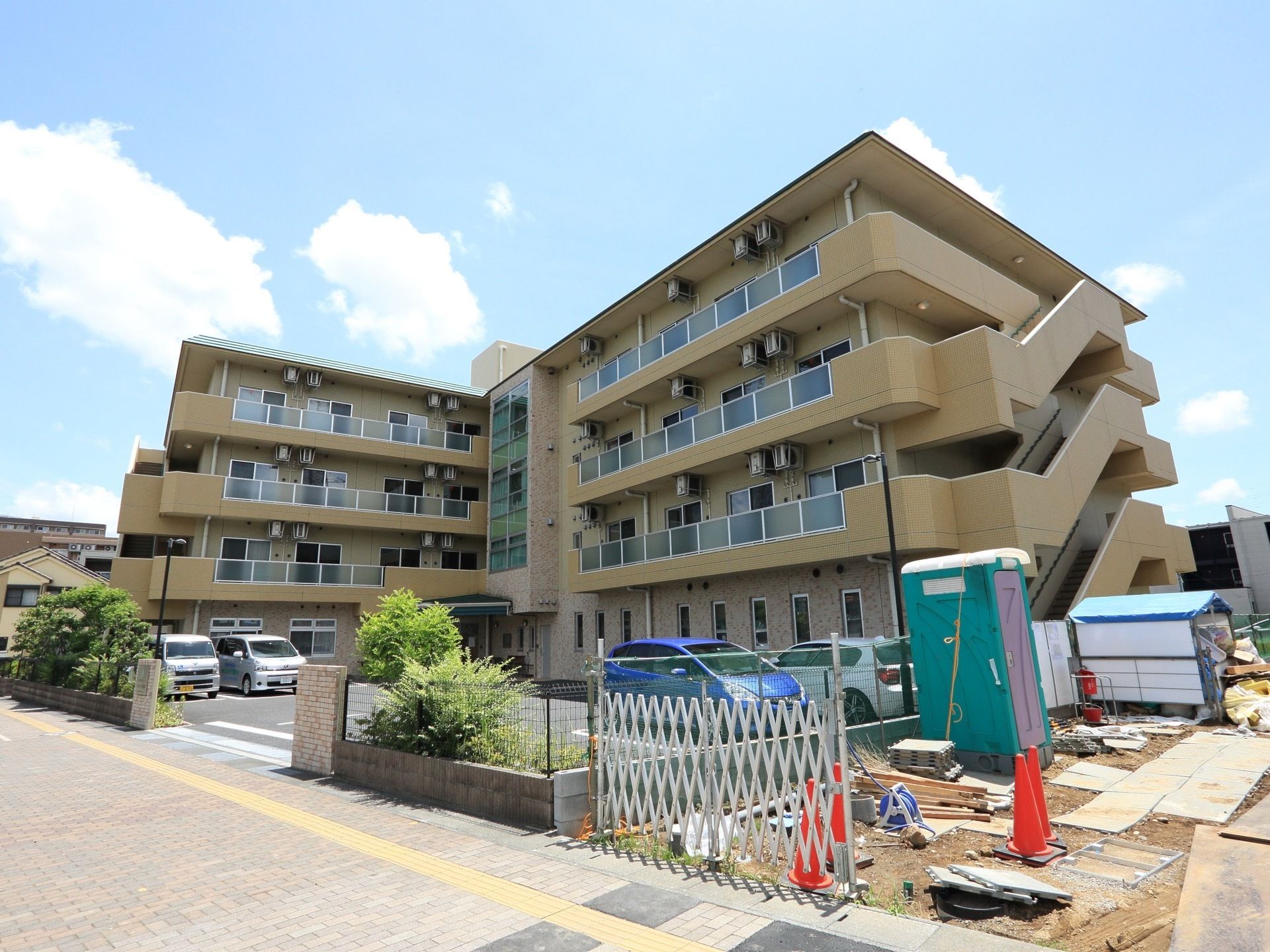 ベージュ色を基調とした４階建てである。敷地が広く、車を複数台駐めることができるだけのスペースがある。