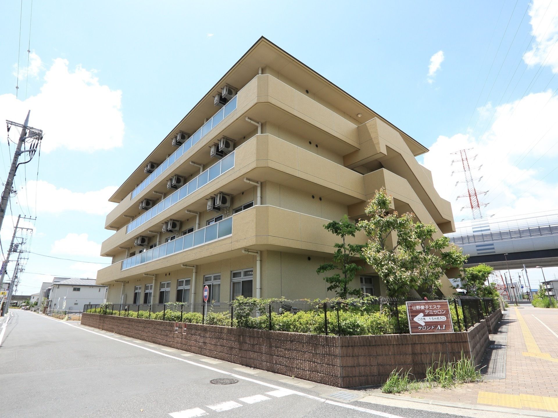 日当たりの良い角地に建てられたベージュの４階建ての建物