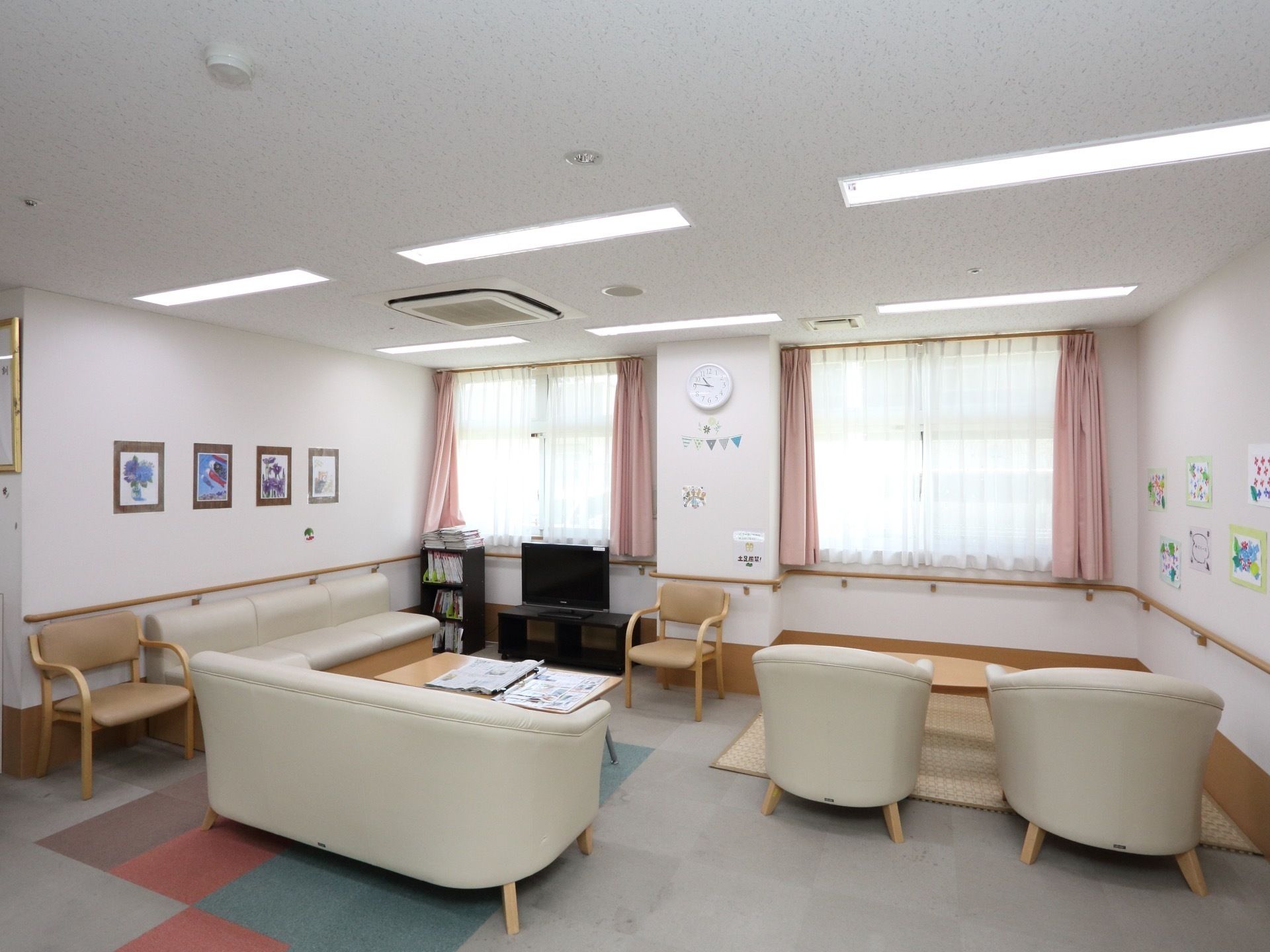 オフホワイトのソファセットやテレビが置かれた明るい応接室