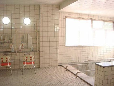 浴槽に手すりが設けられた全面タイル張りの明るい浴室