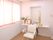 空調のある、フローリングの部屋に洗髪用の椅子と洗面台がある。洗面台の脇に白いカウンターがあり、花が活けられている。
