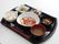炊き込みご飯にお味噌汁、煮込み、おひたし、デザートなど、彩りやバランスを考えた献立がお盆の上に並んでいる。