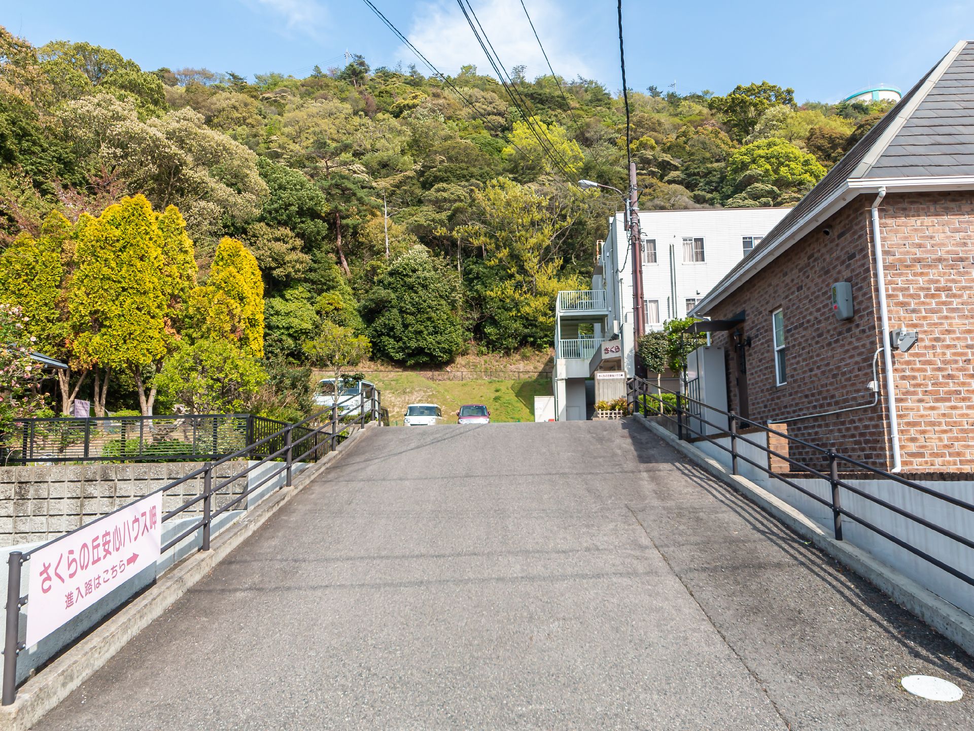玄関正面に駐車場と駐輪場を設置した３階建てタイル張りの建物