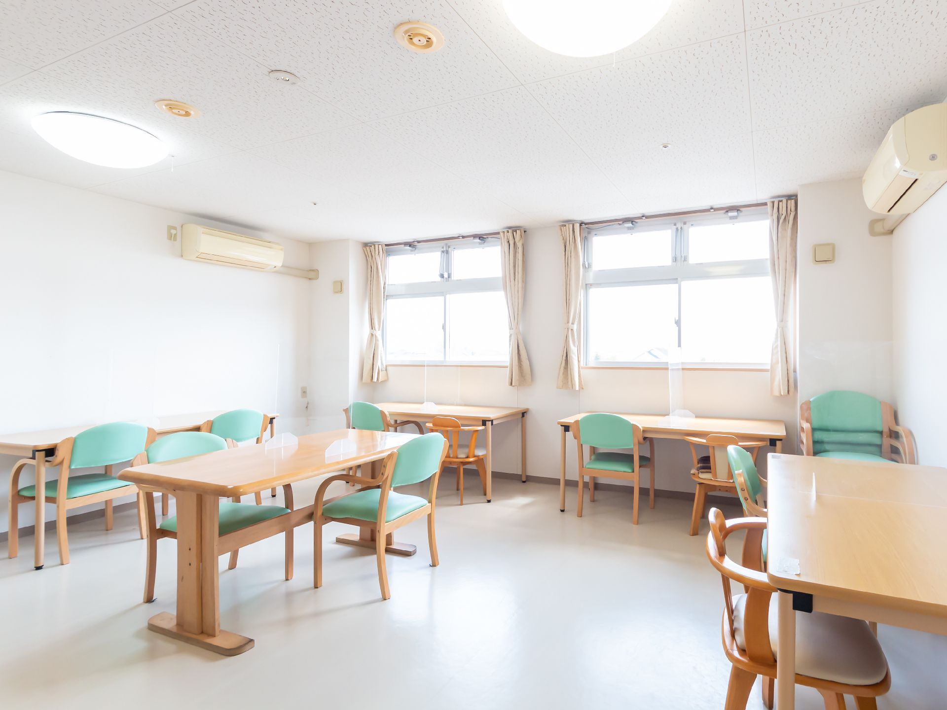 長テーブルが置かれた広い空間に集まり、思い思いに談笑する入居者様