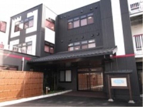 白と黒のデザインが施された外壁に、瓦葺きの玄関ポーチを持つ建物