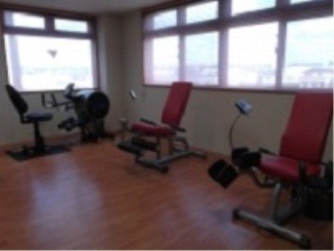 様々な運動器具が配置された木調デザインの床を敷いた部屋