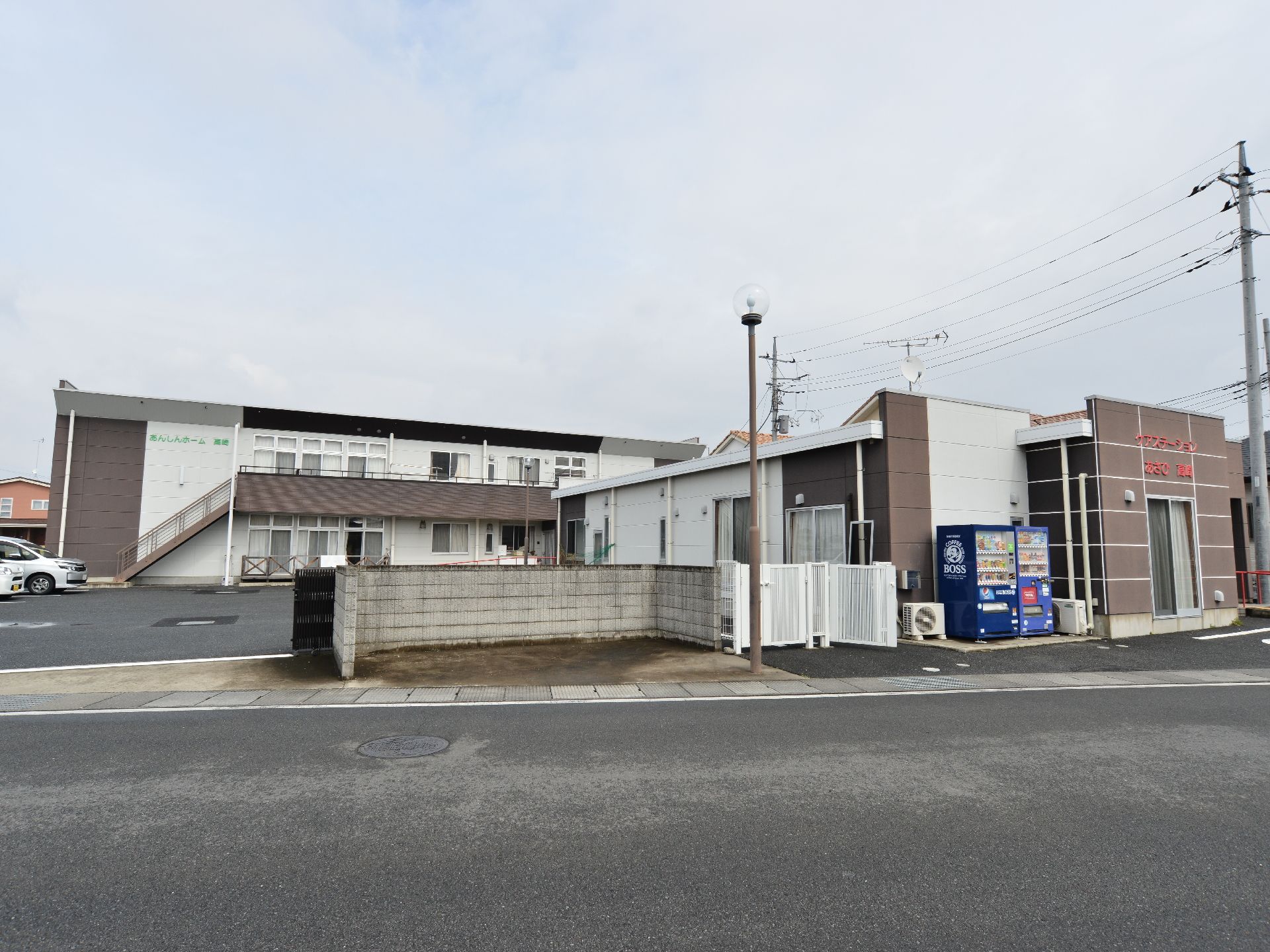 施設前に大きな街灯がある。施設を出たところに、自動販売機が置いてある。ゴミステーションも設置している。