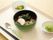 スプーンと箸がお盆にのっている。わかめとかまぼこが乗ったうどんが見える。別の鉢には胡瓜とコーンが入っている。