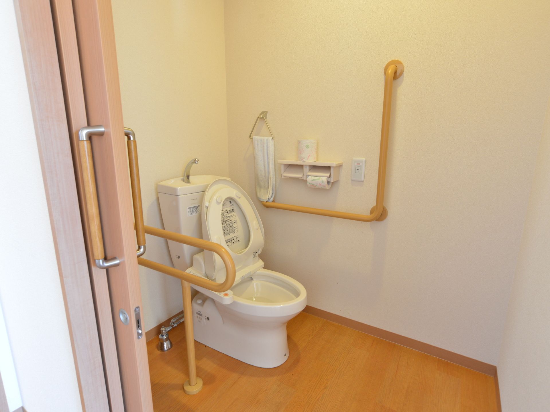トイレの扉は引き戸になっている。トイレにはウォッシュレットと、手洗い場が付いている。両脇に手すりが付いていて、掴まることができる。