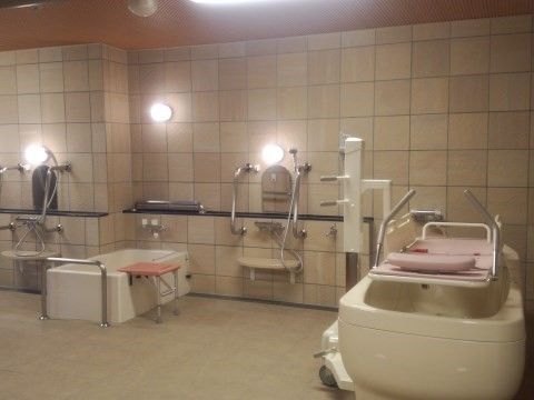 「あんしんホーム磐田福田」の浴室。入浴サポートを行うスタッフが、入居者様のお身体を丁寧に優しく声を掛けながら洗い流す。
