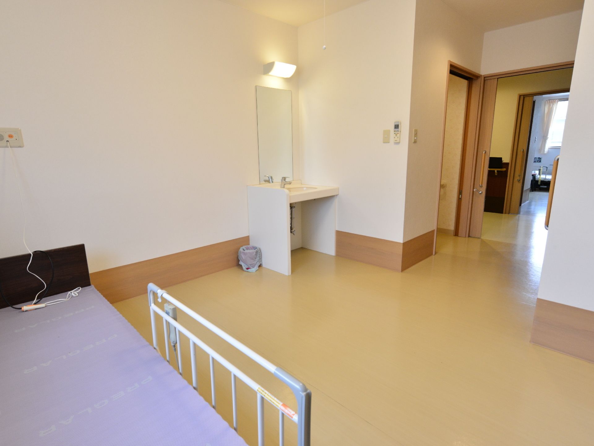 コンパクトな部屋ですが、トイレ、洗面台、ベッドといった生活必需品が揃っている部屋である。床はバリアフリーになっている。