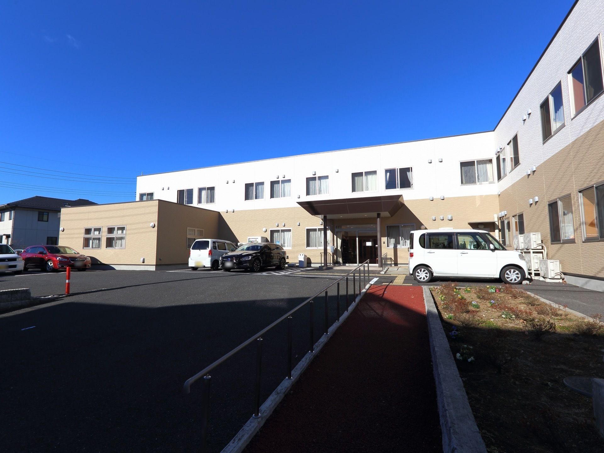 敷地内にスロープを設置している。スロープの横には花壇がある。駐車場もあり、路面はすべて舗装されている。