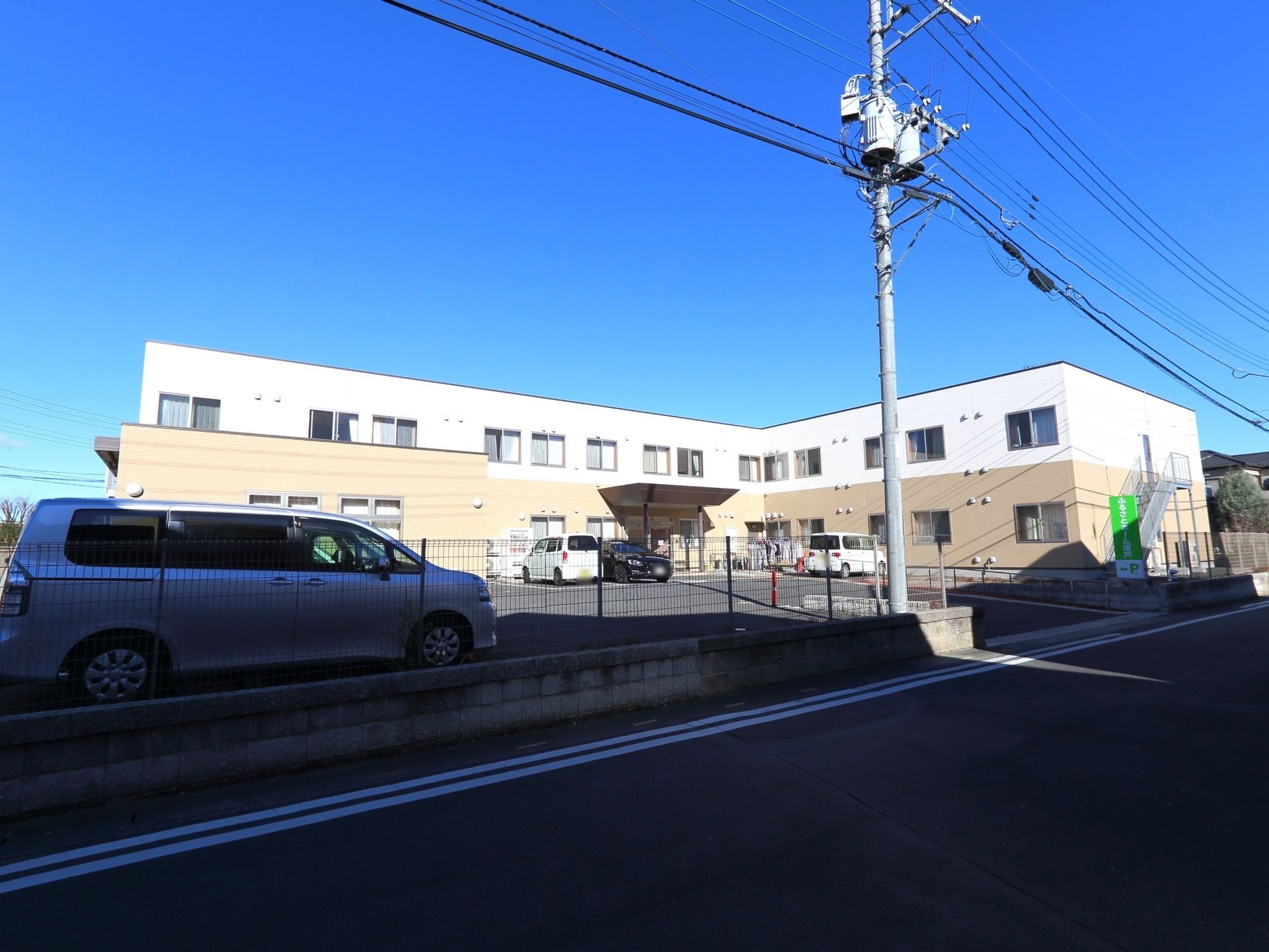 白と茶の色をした、L字型の造りになっている。全体に日差しが当たる建物になっている。広い駐車場がある。